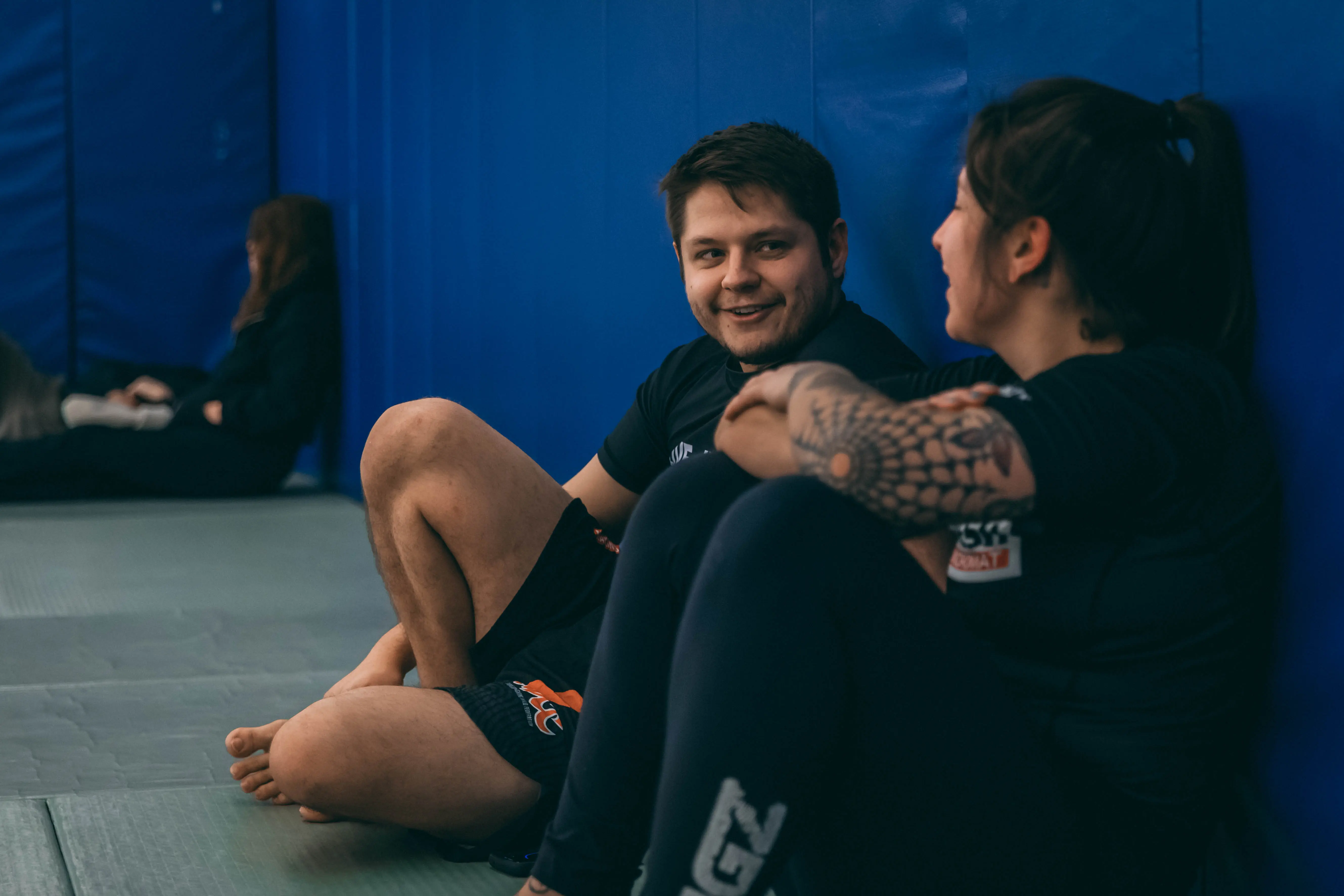 Justin, owner of AliveBJJ sitting with a member on the tatami mats having a conversation